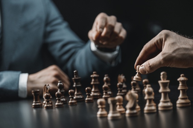 Two people considering their next move on a chessboard
