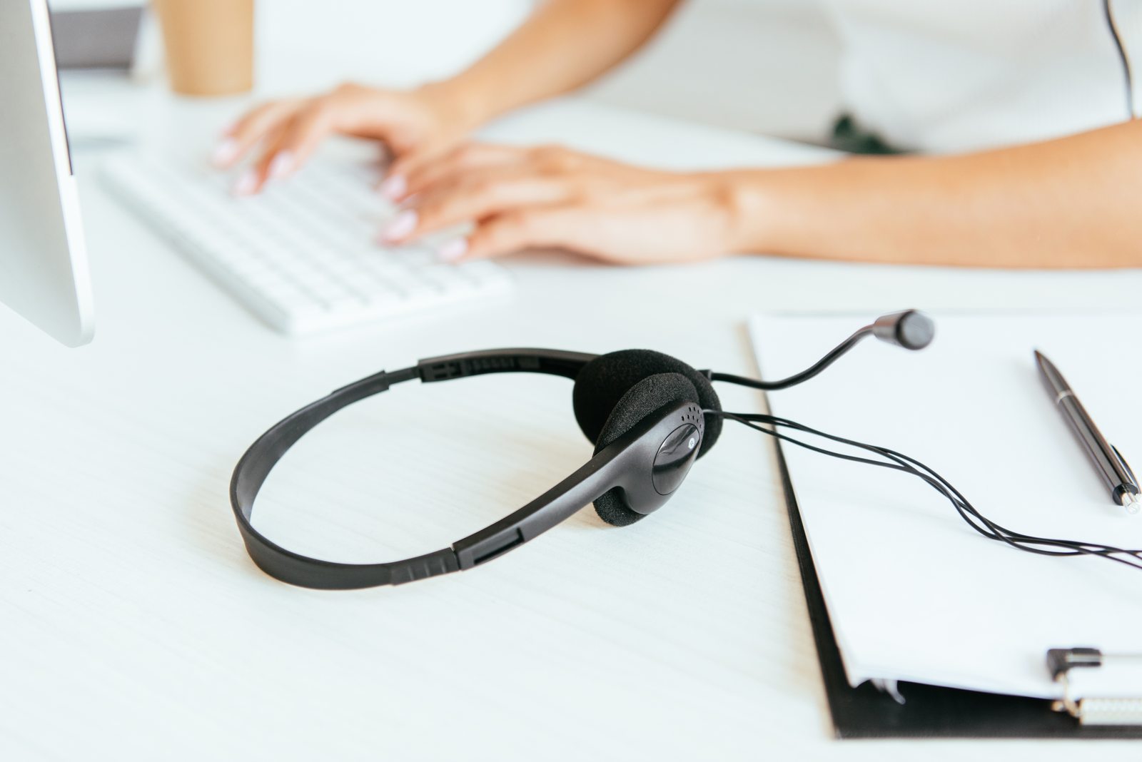 Headset beside a computer and notebook; illustrative photography