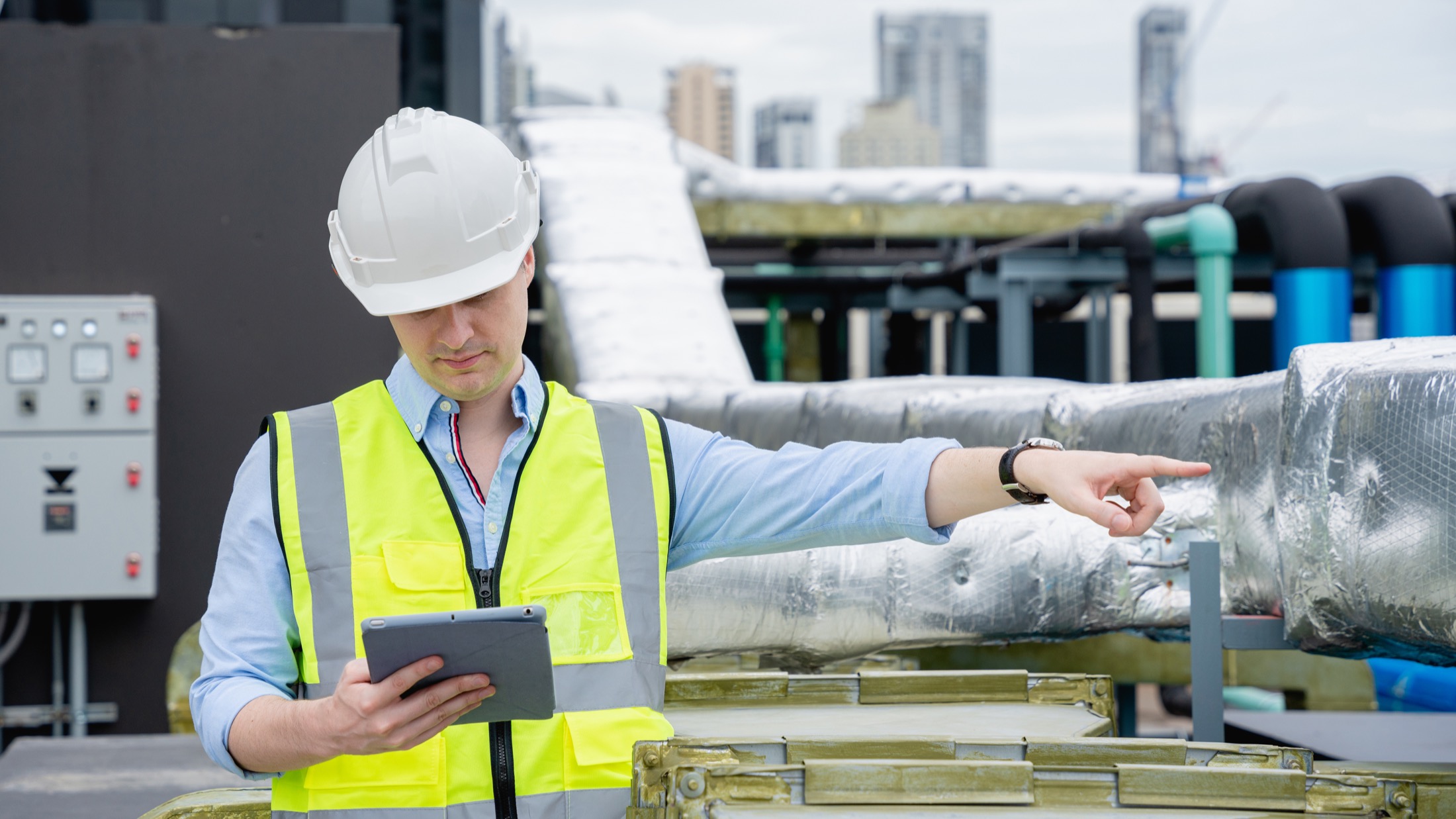 An engineer checking building cooling equipment with a tablet; illustrative stock photograph