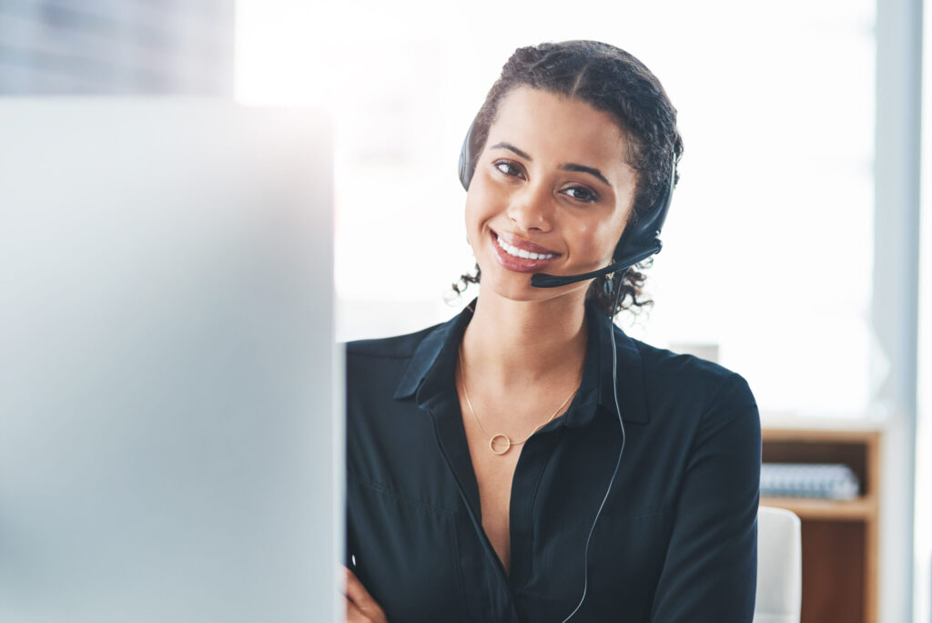 Woman wearing a headset at a computer; illustrative stock photograph