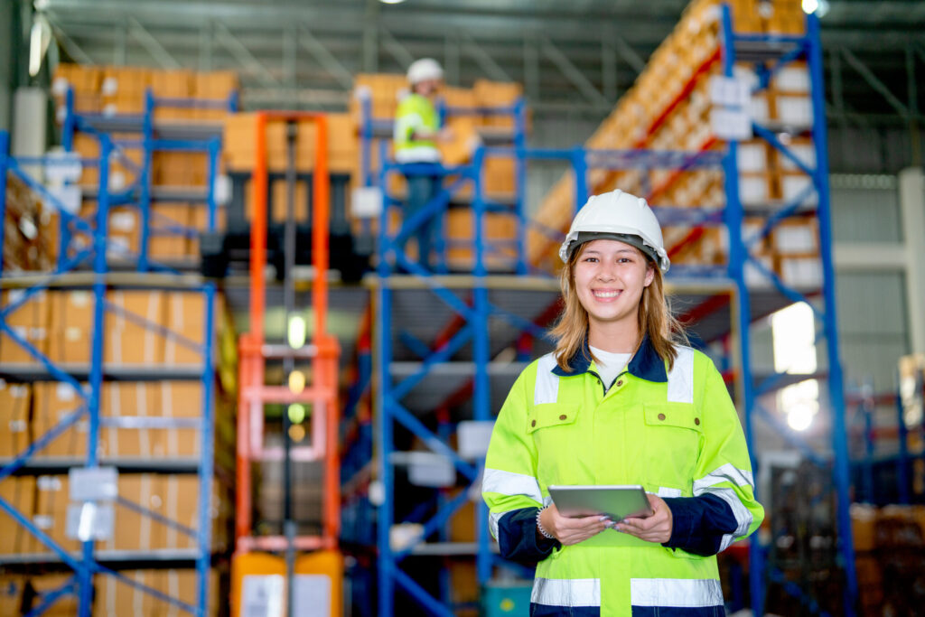 Warehouse employee holding a tablet beside storage racks; illustrative photograph