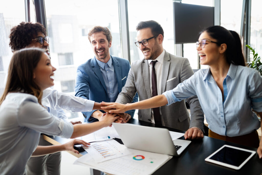 Colleagues joining hands around a table during a team meeting